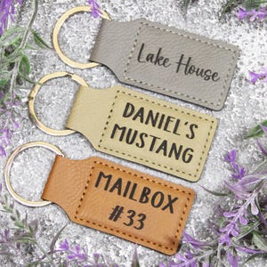 May include: Three leather keychains with gold rings. The keychains are engraved with the text "Lake House", "Daniel's Mustang", and "Mailbox #33".
