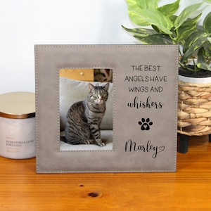 May include: A gray faux leather picture frame with a black paw print and the text "The best angels have wings and whiskers" and "Marley". The frame has a photo of a tabby cat inside.