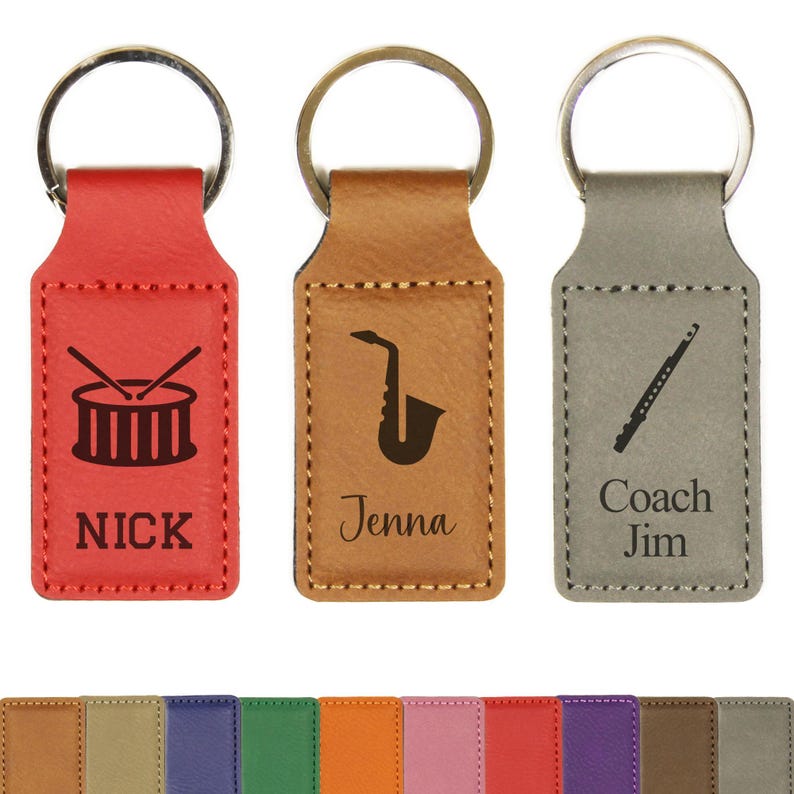 May include: Three leather keychains in red, tan, and gray. Each keychain features a musical instrument graphic: a drum, a saxophone, and a flute. The names "Nick", "Jenna", and "Coach Jim" are engraved below the graphics.