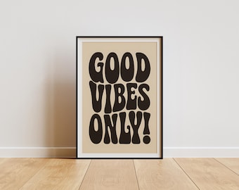 May include: A rectangular wall art print in a thin black frame featuring the text GOOD VIBES ONLY! in large, bold, dark brown, wavy, rounded typography centred on a solid light beige background, creating a high-contrast graphic design.