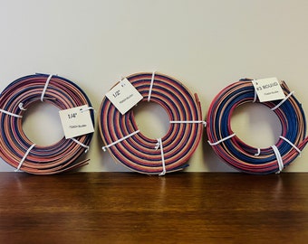 May include: Three spools of peach blush colored raffia ribbon. The spools are labeled 1/4", 1/2", and #3 Round.