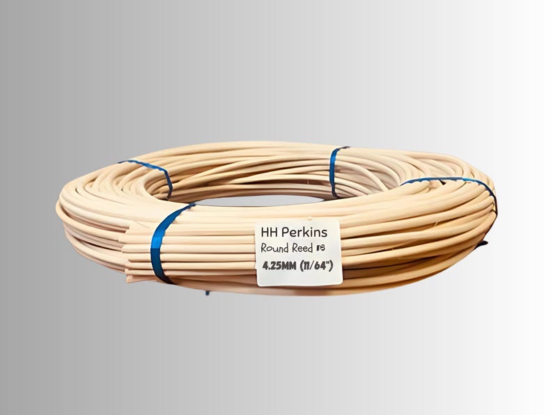 May include: A bundle of HH Perkins Round Reed, tied with blue ribbon. The reed is a light tan color and is labeled as 4.25mm (11/64"). This product is likely used for weaving or crafting.