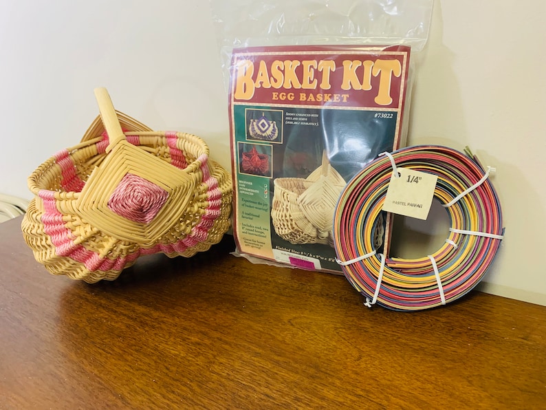 May include: A basket weaving kit with a finished egg basket, a roll of 1/4 inch pastel paper reed, and instructions. The kit is labeled "Basket Kit Egg Basket #73022".