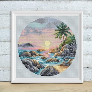 May include: A framed cross-stitch artwork depicts a tropical beach scene. The design, set within a circular frame, features a sunset over the ocean, with palm trees and rocky shores. The color palette includes blues, pinks, and oranges.