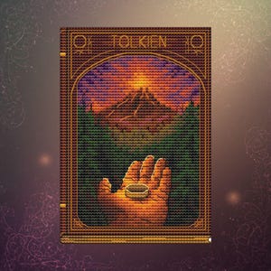 Op de afbeelding: Kruissteekkunst met een hand die een ring vasthoudt, tegen een berglandschap, met de naam "TOLKIEN" erboven. Het stuk gebruikt oranje, groene, paarse en bruine tinten en is omlijst met een gouden rand. Gedetailleerd handwerk.