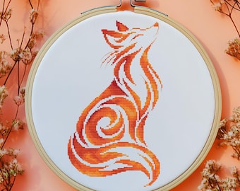 May include: A cross-stitch embroidery of a fox in shades of orange and red, set in a wooden hoop. The fox is depicted in a stylized, flowing design against a white background. The embroidery is a handmade craft project.
