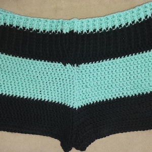 May include: Black and turquoise striped crocheted shorts. The shorts are made with a simple stitch and have a relaxed fit.