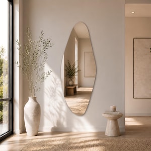 Large frameless geometric organic wall mirror featuring a tall sculptural silhouette with softly faceted contours and polished edges. Crafted from premium-quality mirror glass, it delivers a bright, natural reflection while adding artistic depth and visual interest to any space. Ideal for entryways, living rooms, bedrooms, dressing areas, and hallways. Its distinctive contemporary design complements modern, minimalist, Scandinavian, Japandi, and luxury interiors.