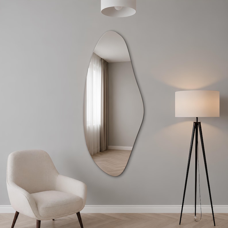 Large frameless geometric organic wall mirror featuring a tall sculptural silhouette with softly faceted contours and polished edges. Crafted from premium-quality mirror glass, it delivers a bright, natural reflection while adding artistic depth and visual interest to any space. Ideal for entryways, living rooms, bedrooms, dressing areas, and hallways. Its distinctive contemporary design complements modern, minimalist, Scandinavian, Japandi, and luxury interiors.