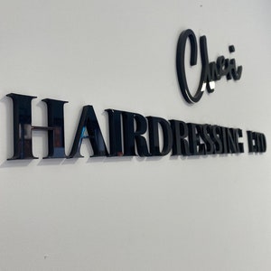 May include: Black and white sign with the text "Cherri Hairdressing Ltd." on a white wall.