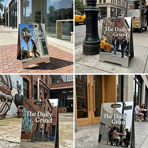 May include: A-frame sign with the text "The Daily Grind" in a modern font. The sign reflects the surrounding urban environment, including buildings and people. The sign is made of a light-colored material.