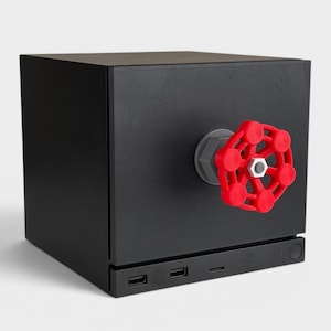 May include: A matte black cubic device featuring a prominent red circular valve handle attached to the front center. The base of the unit includes two USB ports and a small circular button, with a grey mounting component securing the red valve.