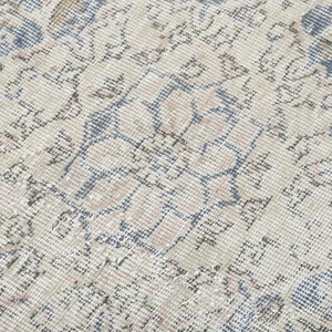 May include: Close-up of a vintage rug with a faded floral pattern in shades of blue, beige, and gray.