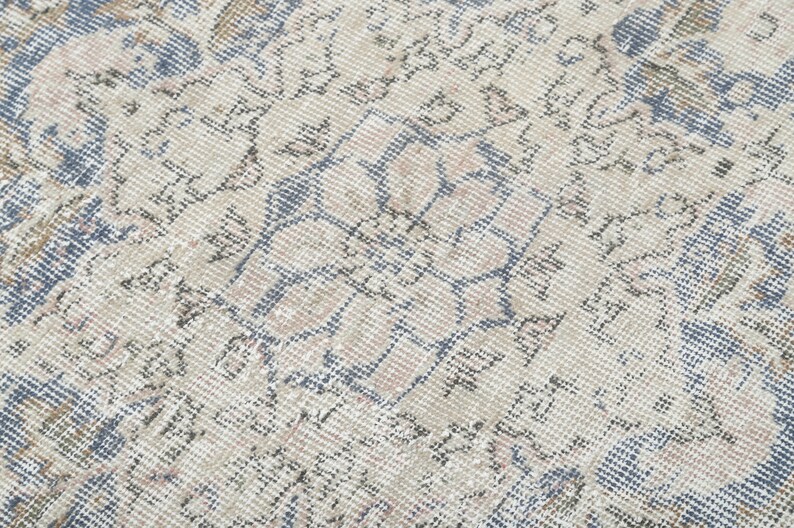 May include: Close-up of a vintage rug with a faded floral pattern in shades of blue, beige, and gray.