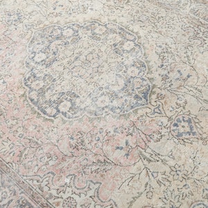 May include: A vintage rug with a faded floral pattern in shades of pink, blue, and cream. The rug has a central medallion with a more intricate design.