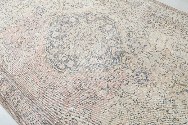 May include: A vintage rug with a faded floral pattern in shades of pink, blue, and cream. The rug has a central medallion with a more intricate design.