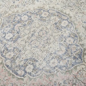 May include: A vintage rug with a faded floral pattern in shades of blue, pink, and beige. The rug has a distressed look and a worn texture.