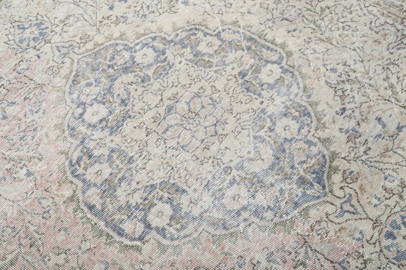 May include: A vintage rug with a faded floral pattern in shades of blue, pink, and beige. The rug has a distressed look and a worn texture.