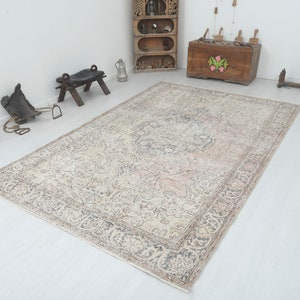 May include: A vintage rug with a cream background and a faded floral pattern in shades of pink, gray, and brown. The rug has a distressed look and is perfect for adding a touch of vintage charm to any room.