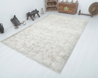 May include: A light gray and white vintage rug with a floral pattern. The rug has a distressed look and is made of wool.