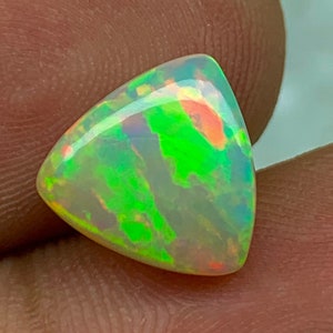 May include: A triangular, iridescent opal gemstone with a green, orange, and white colour pattern.