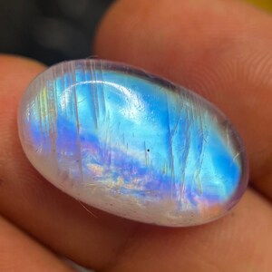 May include: A smooth, oval-shaped, iridescent gemstone with a blue and white colour scheme. The gemstone has a rainbow sheen and is a popular choice for jewellery and crystal healing.