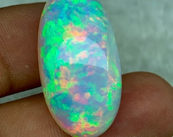 May include: A white oval opal gemstone with green, blue, and pink iridescent flashes.