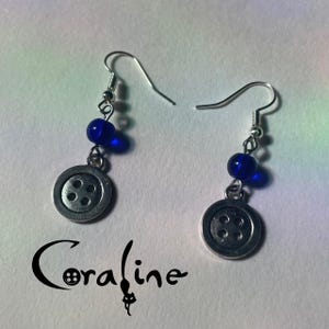 May include: A pair of silver earrings with blue glass beads and silver buttons. The buttons have four holes each.