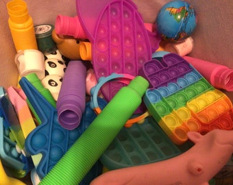 May include: A variety of colorful sensory toys, including pop-it fidget toys, a globe, and a long green tube. The toys are in a basket or bin.
