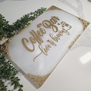 May include: A rectangular white serving tray with gold glitter trim and gold lettering that reads "Coffee Bar Love is brewing". The tray has a white and gold marbled design.