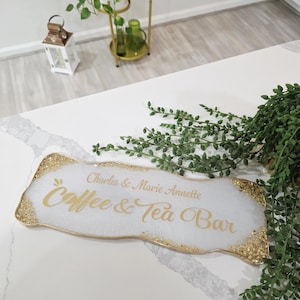 May include: A white resin sign with gold glitter edging, featuring the text "Charles & Marie Annette Coffee & Tea Bar" in gold script. The sign is rectangular with organic edges, suitable for a home coffee station.