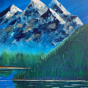 May include: An acrylic painting depicts a mountain landscape. Three snow-capped peaks dominate the scene, with a forest and lake in the foreground. The sky is a deep blue, and the water reflects the trees and mountains.