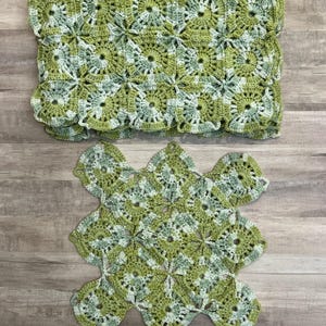 May include: Two handmade crochet items in shades of green and white. The top item is a folded blanket with a scalloped edge. The bottom item is a smaller, decorative piece with a floral pattern. Both items are made with a granny square design.