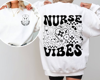 Könnte beinhalten: Weißes Sweatshirt mit einem schwarz-weißen Grafikdesign. Auf der Vorderseite befindet sich ein kleiner Smiley mit einer Krankenschwestermütze und den Worten "Nurse Vibes". Auf der Rückseite stehen die Worte "Nurse Vibes" und medizinische Illustrationen.
