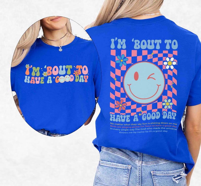 May include: A royal blue t-shirt with the text "I'M 'BOUT TO HAVE A GOOD DAY" in a retro font. The back of the shirt features a smiley face and a checkered pattern with flowers. The shirt has short sleeves.