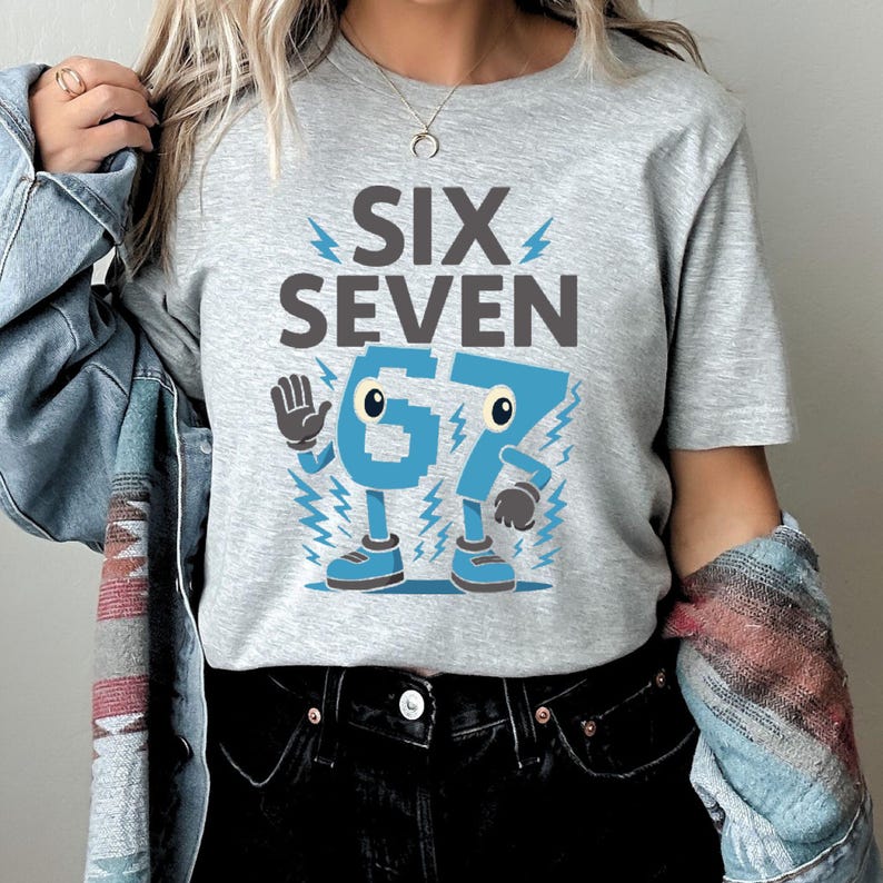 May include: A light gray t-shirt with the words "SIX SEVEN" above the number "67" in blue. The number "67" has cartoon-like features, including eyes, arms, legs, and shoes. Blue lightning bolts surround the numbers.