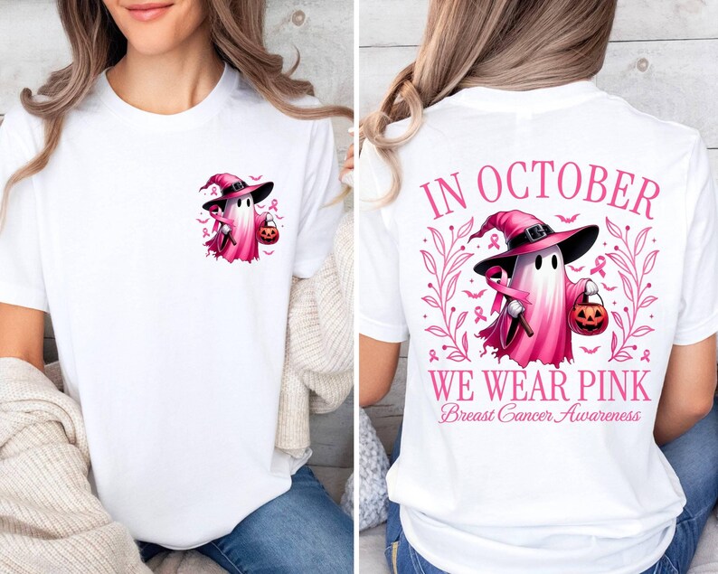May include: White t-shirt featuring a pink ghost wearing a witch's hat and carrying a pumpkin. The back of the shirt reads "In October We Wear Pink Breast Cancer Awareness".