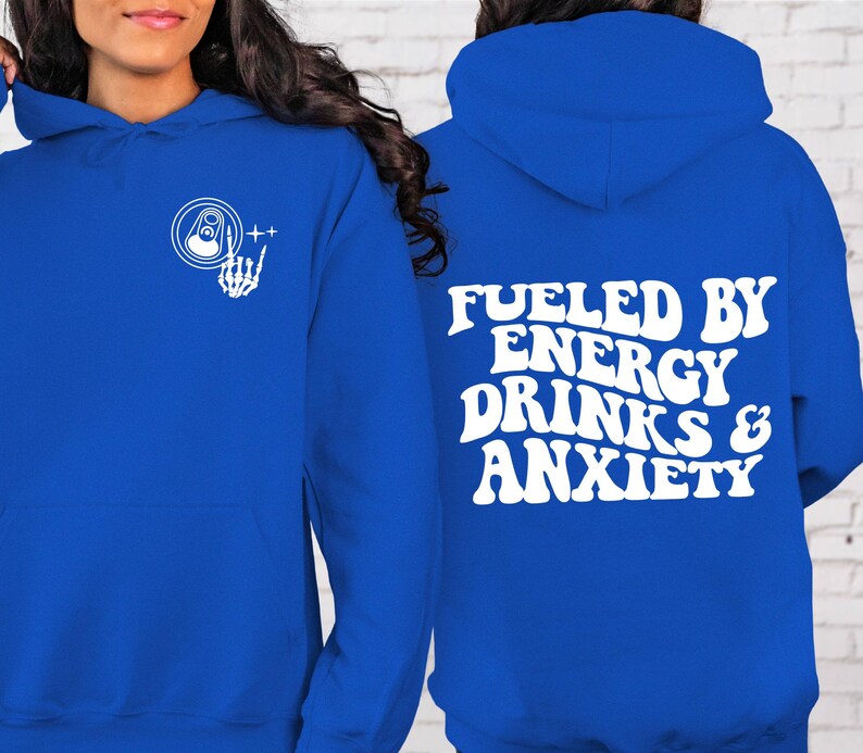 Puede incluir: Una sudadera con capucha azul real con texto blanco que dice "Fueled by Energy Drinks & Anxiety". La parte delantera de la sudadera tiene un gr&aacute;fico blanco de una mano de esqueleto sosteniendo una lata con una pesta&ntilde;a de apertura.