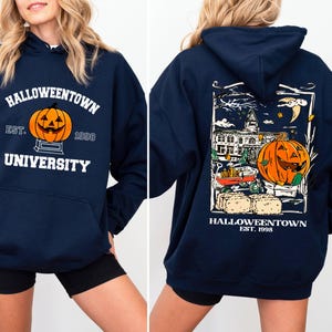 May include: Navy blue hooded sweatshirt with "Halloweentown University" and a jack-o'-lantern graphic on the front. The back features a Halloween-themed illustration with a pumpkin, buildings, and the text "Halloweentown Est. 1998."
