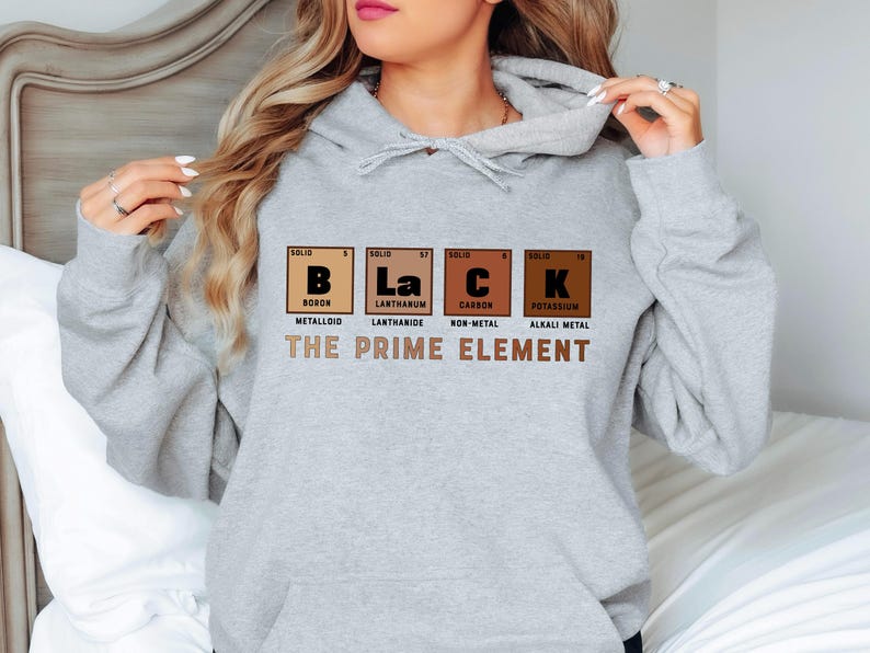 Puede incluir: Sudadera gris con capucha con el texto "BLACK" escrito usando los s&iacute;mbolos qu&iacute;micos de boro, lantano, carbono y potasio. El texto "THE PRIME ELEMENT" est&aacute; impreso debajo de los s&iacute;mbolos qu&iacute;micos.