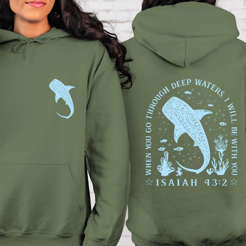 May include: Olive green hoodie featuring a light blue whale shark graphic on the front and back. The back design includes the text "WHEN YOU GO THROUGH DEEP WATERS I WILL BE WITH YOU" and "ISAIAH 43:2". The hoodie has a kangaroo pocket and a hood.