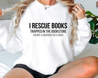 May include: White sweatshirt with the text "I rescue books trapped in the bookstore I'm not a hoarder I'm a hero" printed on the front.