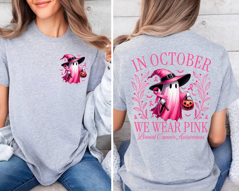 May include: Grey t-shirt with a pink ghost wearing a witch hat and holding a pumpkin. The text on the back of the shirt reads "In October We Wear Pink Breast Cancer Awareness."