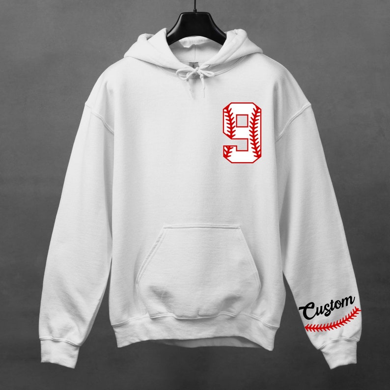 K&ouml;nnte beinhalten: Wei&szlig;er Kapuzenpullover mit einer roten Baseballnummer 9 auf der Vorderseite und dem Wort "Custom" mit einem roten Baseball-Stichdesign auf dem &Auml;rmel.