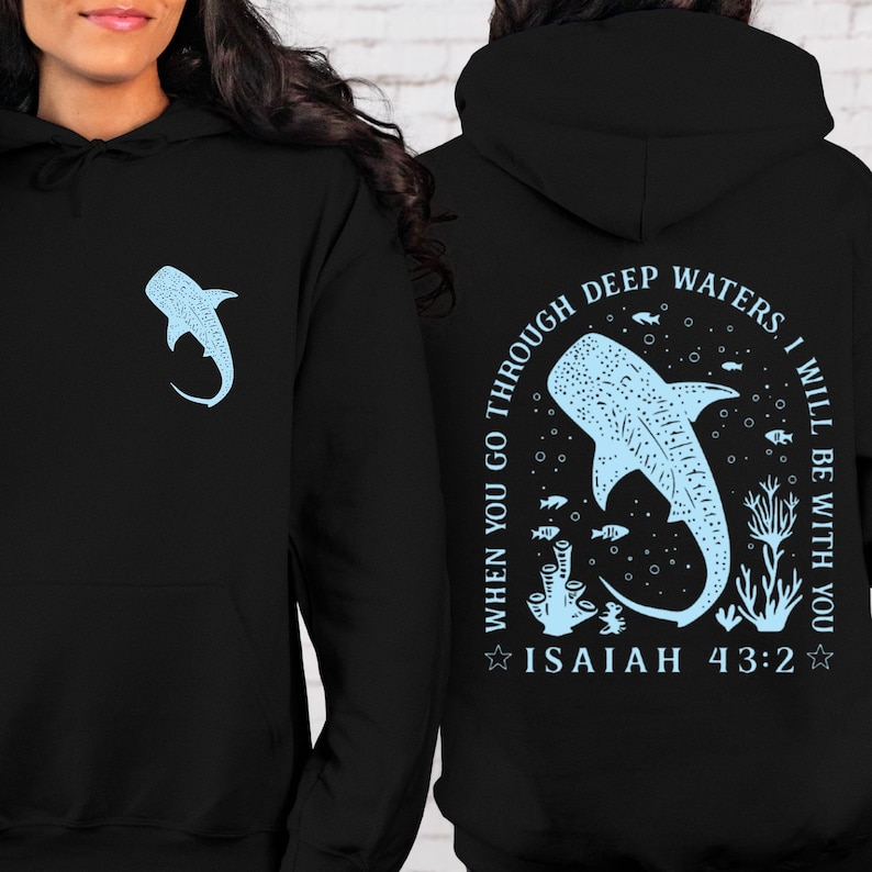 May include: Black hoodie with a light blue whale shark graphic on the front and back. The back design includes the text "WHEN YOU GO THROUGH DEEP WATERS, I WILL BE WITH YOU" and "ISAIAH 43:2". The hoodie has a drawstring hood and a kangaroo pocket.