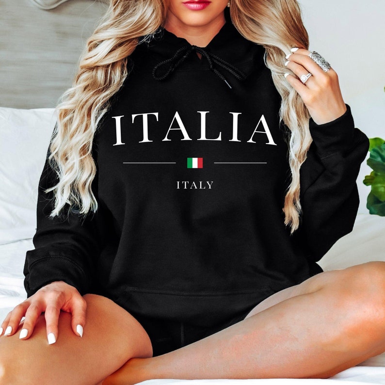 May include: Black hoodie with the word "ITALIA" in white, above a horizontal line, the Italian flag, and the word "ITALY". The hoodie has a drawstring and is made of a soft material.