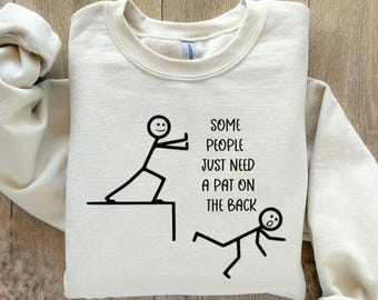 May include: A beige sweatshirt with a stick figure illustration and the text "Some people just need a pat on the back".