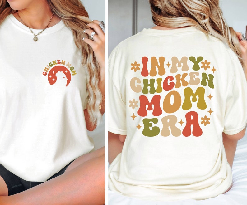 May include: White t-shirt with the text "Chicken Mom Era" in colorful retro font. The text is surrounded by stars and flowers.