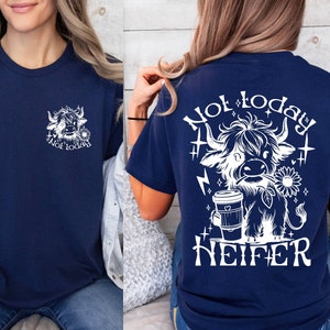 May include: A navy blue t-shirt with a white graphic of a Highland cow holding a coffee cup and the text "Not today heifer".