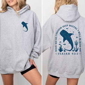 May include: A light gray hoodie with a front pocket and a hood. The front features a dark blue whale shark graphic. The back of the hoodie has a larger whale shark design with the text "WHEN YOU GO THROUGH DEEP WATERS, I WILL BE WITH YOU" and "ISAIAH 43:2".